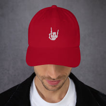 Load image into Gallery viewer, Man modeling/wearing Cranberry Red Baseball cap, classic visor shape. Image Design: "Rock On" skeleton hand gesture on the front. Front center view.