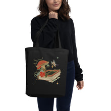 Load image into Gallery viewer, woman modeling/holding black tote bag, certified organic, with Image Design: Old book, vial, mushroom, and butterfly with a vintage look