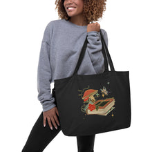 Load image into Gallery viewer, woman modeling/holding Large black tote bag, cotton, certified organic, with Image Design: Old book, vial, mushroom, and butterfly with a vintage look
