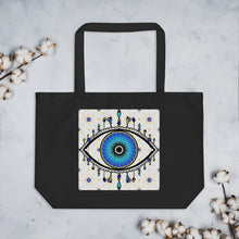 Load image into Gallery viewer, large black colored tote bag with image of eye of protection/evil eye, colors of golden yellow, blue, light blue, third eye, eye, celestial stars. certified organic, cotton.