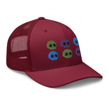 Load image into Gallery viewer, retro trucker hat cranberry red, with image design of 6 purple, green, and blue skulls, 2 of each color, in two rows. side view.