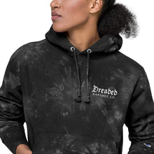 Load image into Gallery viewer, Woman modeling/wearing dark grey and black, unisex champion tie-dye hoodie, with pockets. Embroidered logo of "Dreaded Banshee Co." on left hand breast side. Front view. Close up.