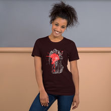 Load image into Gallery viewer, woman modeling/wearing unisex oxblood black t-shirt, with image design of an angel kissing a woman, with a red paint splat seen through their outlines. Front view.