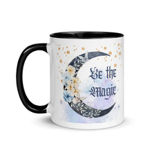 Load image into Gallery viewer, 11 oz. white ceramic coffee/tea mug with solid black handle, rim, and inside. Image Design: watercolor blue crescent moon, with flowers, daisies, lilies, butterflies. Stars in background, smoky purple background. Image phrase: Be the Magic. left hand side view. Halloween, spooky season.