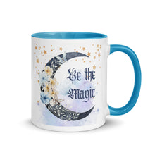 Load image into Gallery viewer, 11 oz. white ceramic coffee/tea mug with solid light blue handle, rim, and inside. Image Design: watercolor blue crescent moon, with flowers, daisies, lilies, butterflies. Stars in background, smoky purple background. Image phrase: Be the Magic. Right hand side view. Halloween, spooky season.