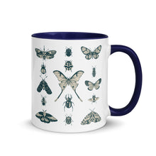Load image into Gallery viewer, 11 oz. white ceramic coffee/tea mug with solid navy blue handle, rim, and inside. Image Design: vintage beige and blue print images of various moths, butterflies, and beetles, all arranged in rows and columns. Right hand side view. Halloween, spooky season.