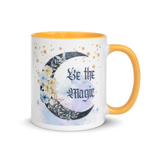 Load image into Gallery viewer, 11 oz. white ceramic coffee/tea mug with solid golden yellow handle, rim, and inside. Image Design: watercolor blue crescent moon, with flowers, daisies, lilies, butterflies. Stars in background, smoky purple background. Image phrase: Be the Magic. Right hand side view. Halloween, spooky season.