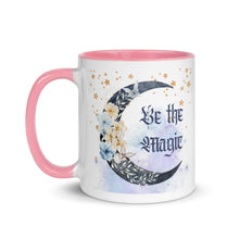 Load image into Gallery viewer, 11 oz. white ceramic coffee/tea mug with solid light pink handle, rim, and inside. Image Design: watercolor blue crescent moon, with flowers, daisies, lilies, butterflies. Stars in background, smoky purple background. Image phrase: Be the Magic. left hand side view. Halloween, spooky season.