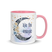 Load image into Gallery viewer, 11 oz. white ceramic coffee/tea mug with solid light pink handle, rim, and inside. Image Design: watercolor blue crescent moon, with flowers, daisies, lilies, butterflies. Stars in background, smoky purple background. Image phrase: Be the Magic. Right hand side view. Halloween, spooky season.