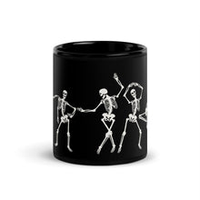 Load image into Gallery viewer, 11 oz. solid black ceramic coffee/tea mug with solid black handle, rim, and inside, outside. Image Design:  
 white minimalist skeletons in line, dancing and posing. Center front view. Halloween, spooky season.
