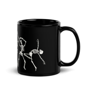 11 oz. solid black ceramic coffee/tea mug with solid black handle, rim, and inside, outside. Image Design:  
 white minimalist skeletons in line, dancing and posing. Right hand side view. Halloween, spooky season.