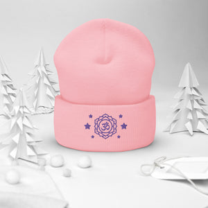 cuffed beanie baby pink, with image design of purple third eye chakra symbol, with purple stars. background: winter themed, Christmas gifts.