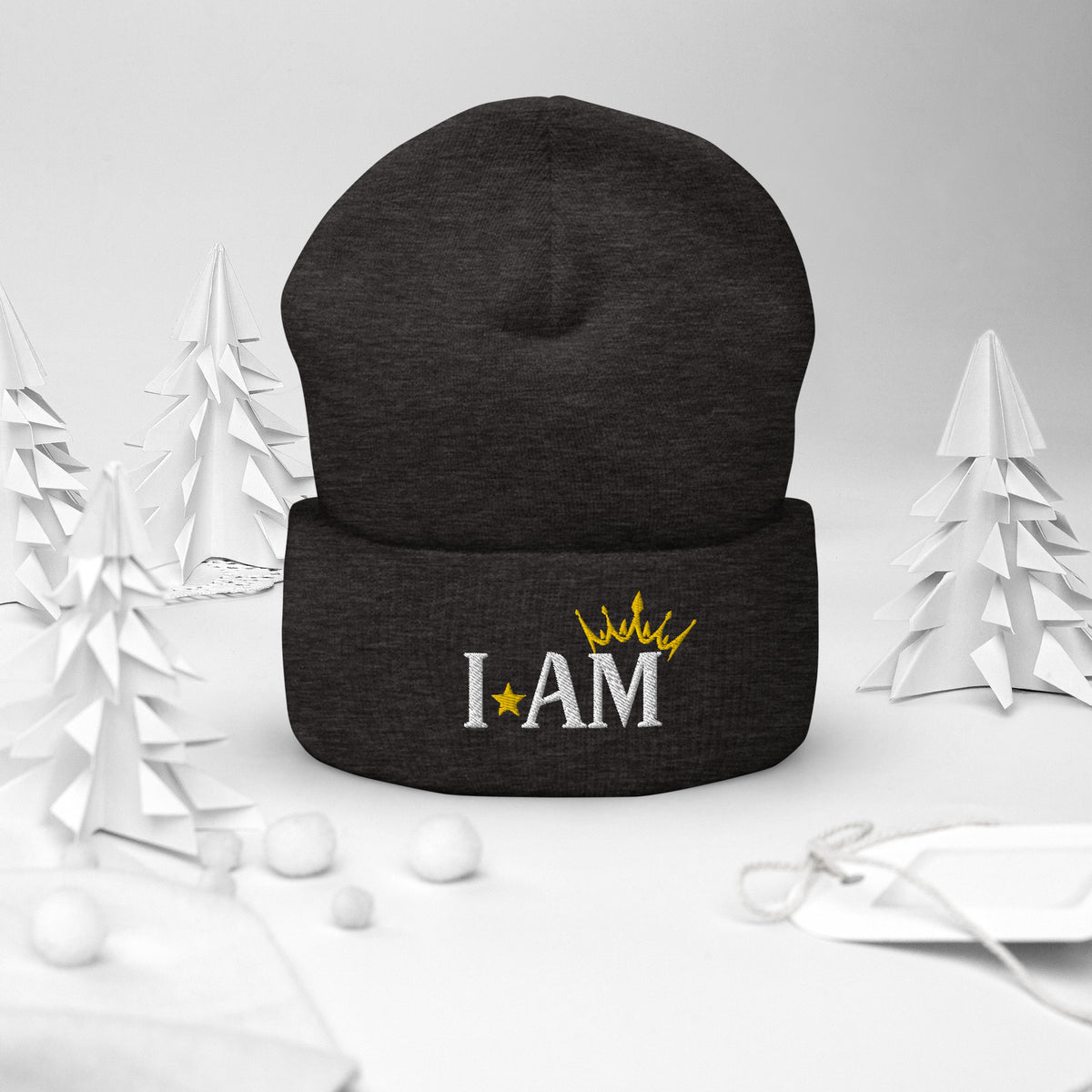 cuffed beanie dark grey, with image phrase "I AM," with image of a crown over the word AM. background: winter themed, Christmas gifts.