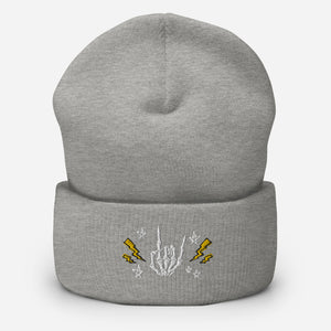 cuffed beanie heather grey, with image design of rock on skeleton hand, pentagram stars, lightning symbols. background: winter themed, Christmas gifts.