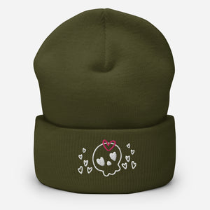 beanie olive green, with image design of a cartoonish cute skull with heart eyes, a heart bow, and stars. Front view.