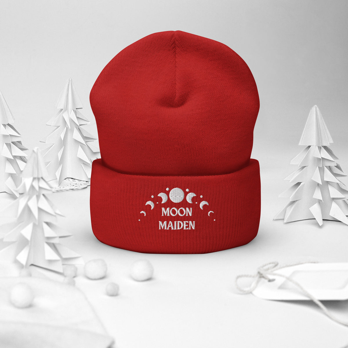 cuffed beanie red, with image phrase "Moon Maiden," and image graphic of moon phases. background: winter themed, Christmas gifts.