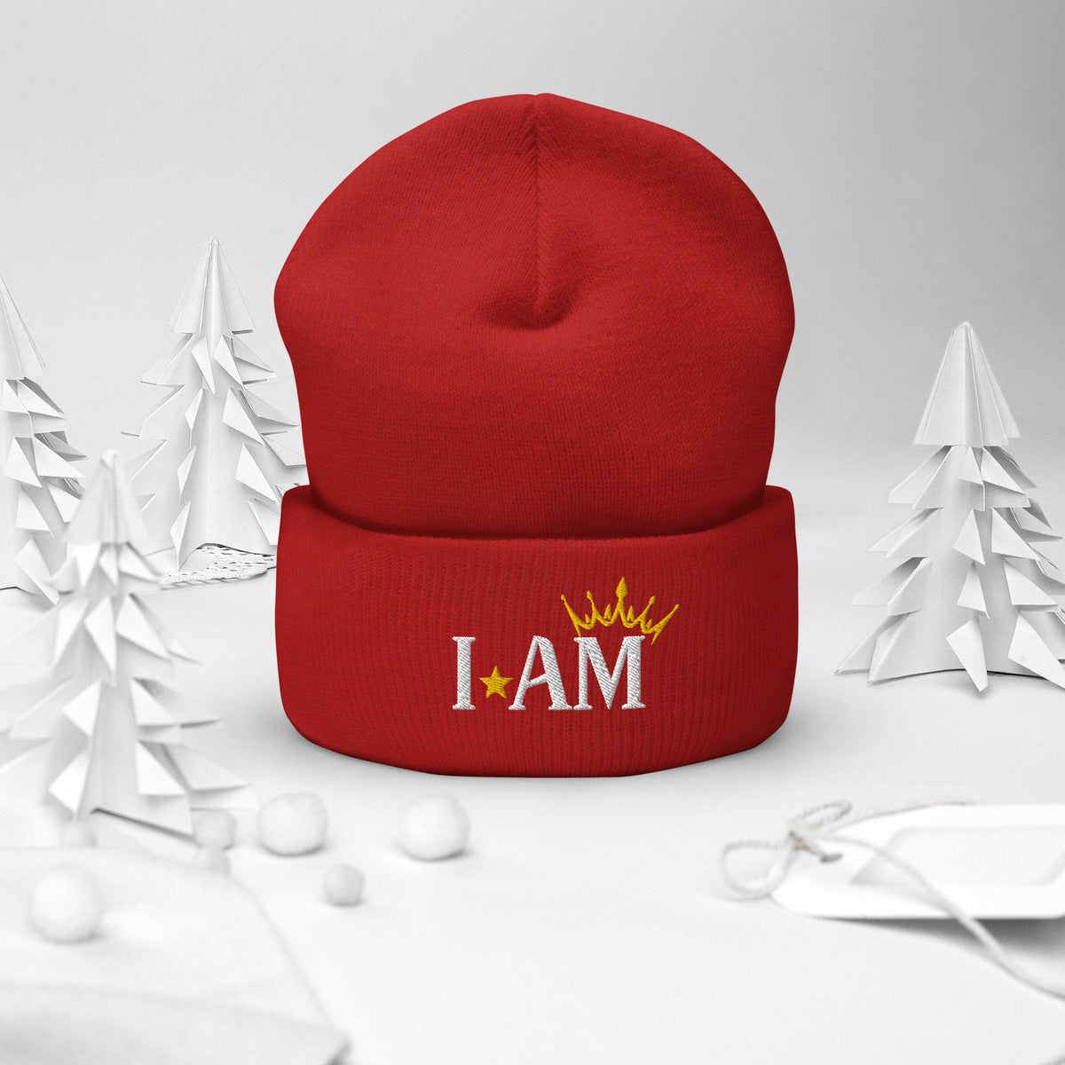 cuffed beanie red, with image phrase "I AM," with image of a crown over the word AM. background: winter themed, Christmas gifts.