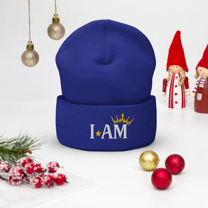 cuffed beanie royal blue, with image phrase "I AM," with image of a crown over the word AM. background: winter themed, Christmas gifts.