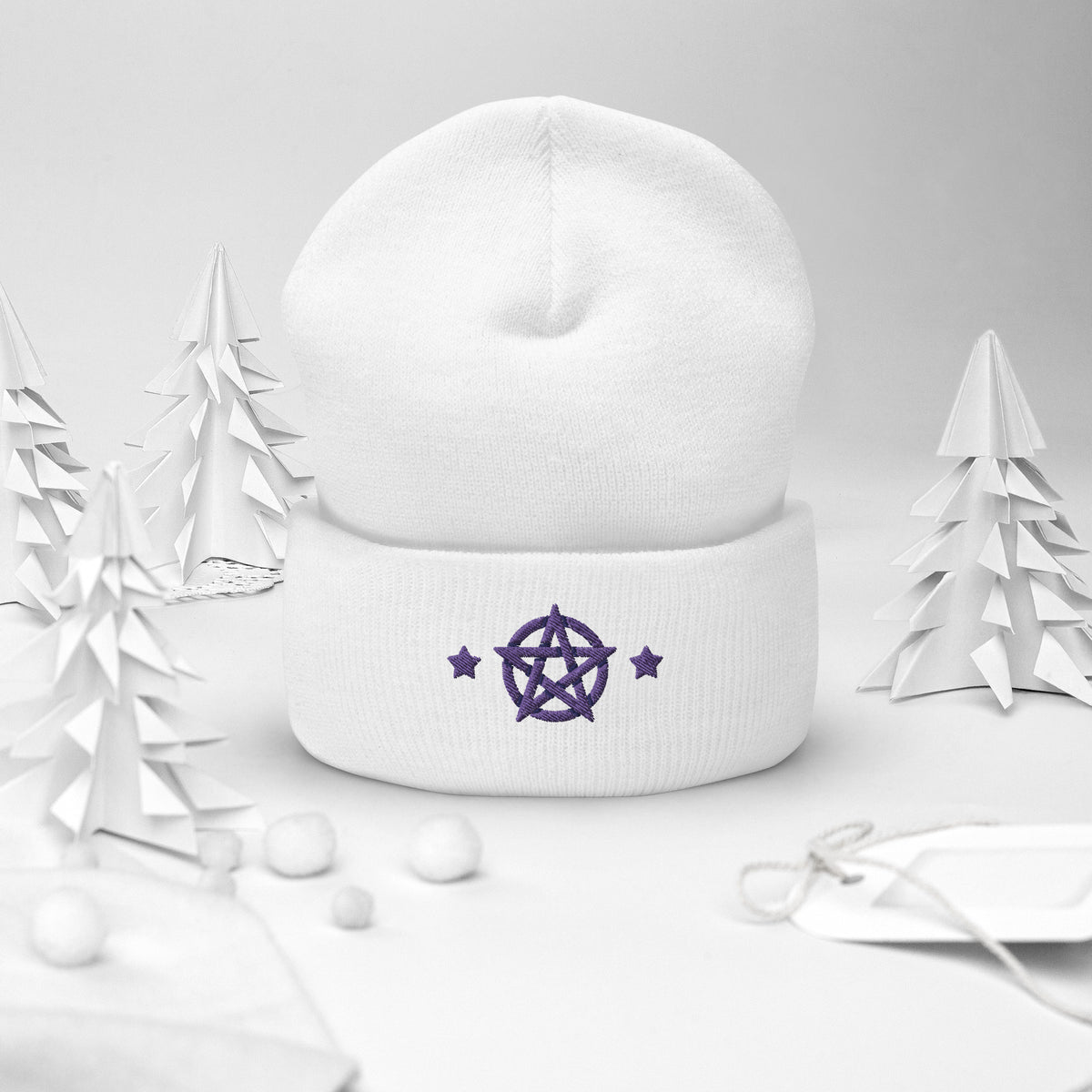 cuffed beanie white, with image design of purple pentacle and stars. background: winter themed, Christmas gifts.