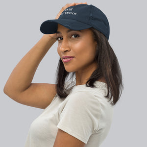 Side view, woman modeling/wearing vintage navy blue distressed hat. Baseball cap. Phrase: 100% That Witch. Featuring bold embroidered white lettering on the front, playful and stylish