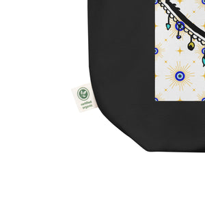 close up image of tag showing certified organic. black colored tote bag with image of eye of protection/evil eye, colors of golden yellow, blue, light blue, third eye, eye, celestial stars. certified organic, cotton.