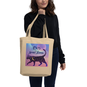 Lady modeling with tote bag, words: cats are my spirit animal, cosmic cat silhouette, cat silhouette, cat outline, moon, stars, purple and blue