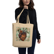 Load image into Gallery viewer, woman modeling/holding oyster colored tote bag, certified organic. Image design: Red illustrated heart with vines and rose, wavy green checkered print background  behind the image
