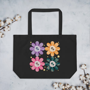 Large Black tote bag, certified organic, watercolor daisies with skull faces at their centers, mix of cute and creepy-cute, purple daisy, orange daisy, fuchsia pink daisy, black daisy. adorned with cute yellow stars.