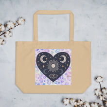 Load image into Gallery viewer, large oyster colored tote bag, certified organic. Image design: blue mystical heart with eye in middle, and crescent moons, and a light purple leopard print background behind the image
