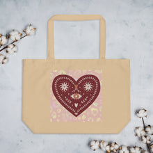 Load image into Gallery viewer, large oyster colored tote bag, certified organic. Image design: boho warm red mystical heart with eye in middle, and daisies, and a light red-gold leopard print background behind the image
