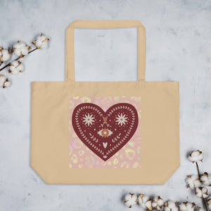 large oyster colored tote bag, certified organic. Image design: boho warm red mystical heart with eye in middle, and daisies, and a light red-gold leopard print background behind the image