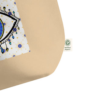 close up image of tag showing certified organic, large oyster colored tote bag with image of eye of protection/evil eye, colors of golden yellow, blue, light blue, third eye, eye, celestial stars. certified organic, cotton.