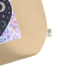 Load image into Gallery viewer, close up of tag, showing certified organic, large oyster colored tote bag, certified organic. Image design: blue mystical heart with eye in middle, and crescent moons, and a light purple leopard print background behind the image
