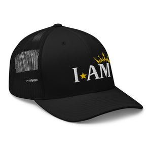 retro trucker hat black, with image phrase: "I AM," with image graphic of a gold crown over the letter M. side view.