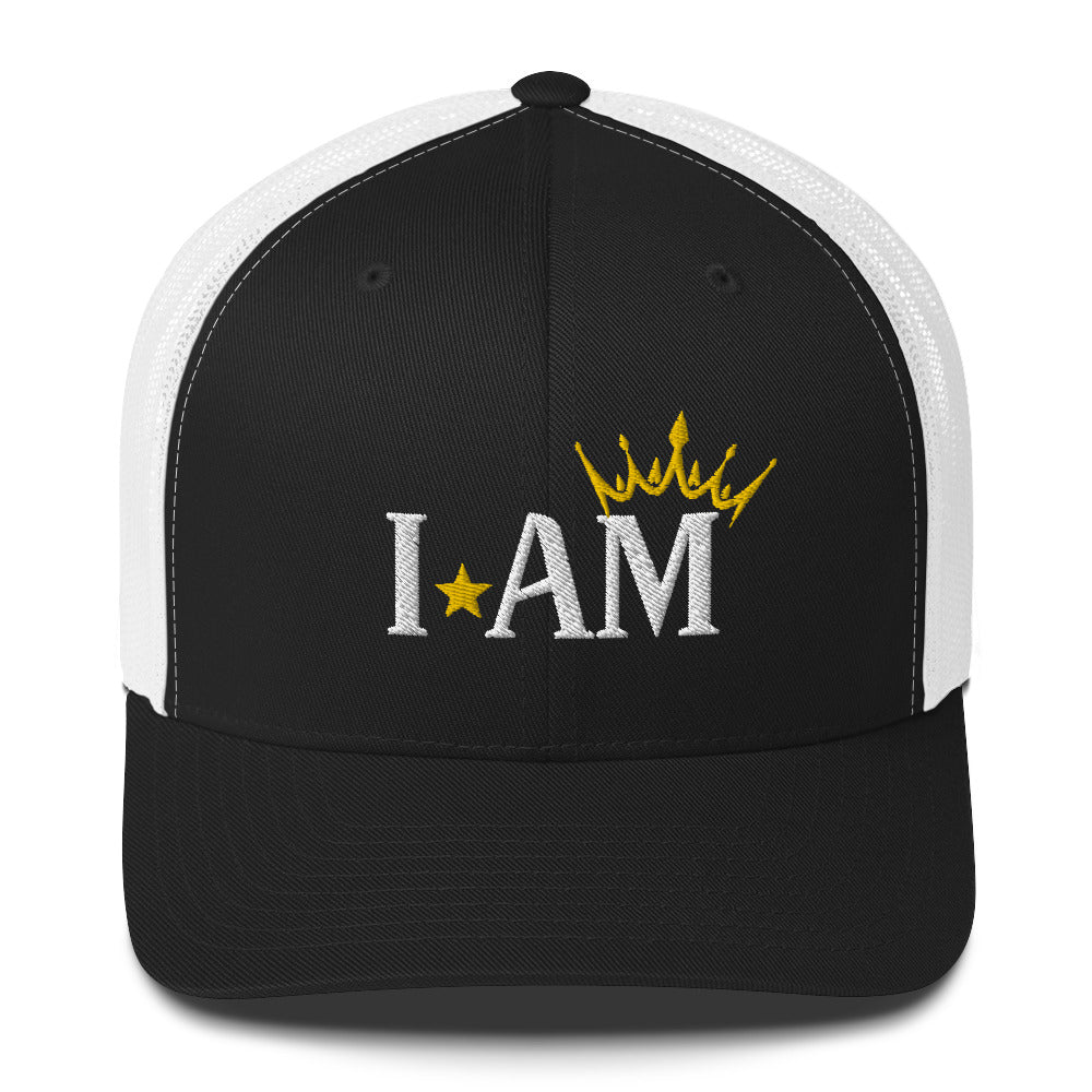 retro trucker hat black white, with image phrase: "I AM," with image graphic of a gold crown over the letter M. Front view.