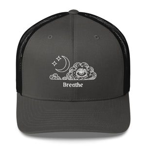 retro trucker hat/cap charcoal grey black, with image design of an eye in a cloud, with moon crescent and stars, with the word "Breathe" underneath the image.  Front view.