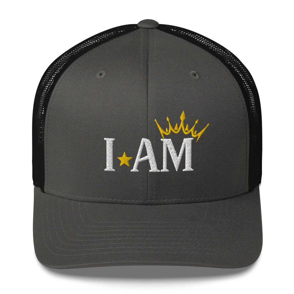 retro trucker hat charcoal grey black, with image phrase: "I AM," with image graphic of a gold crown over the letter M. Front view.