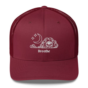 retro trucker hat/cap cranberry red, with image design of an eye in a cloud, with moon crescent and stars, with the word "Breathe" underneath the image.  Front view.