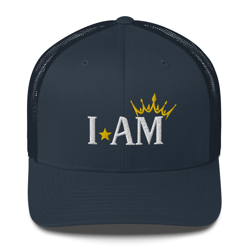 retro trucker hat navy blue, with image phrase: "I AM," with image graphic of a gold crown over the letter M. Front view.