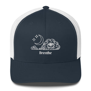 retro trucker hat/cap navy blue white, with image design of an eye in a cloud, with moon crescent and stars, with the word "Breathe" underneath the image.  Front view.