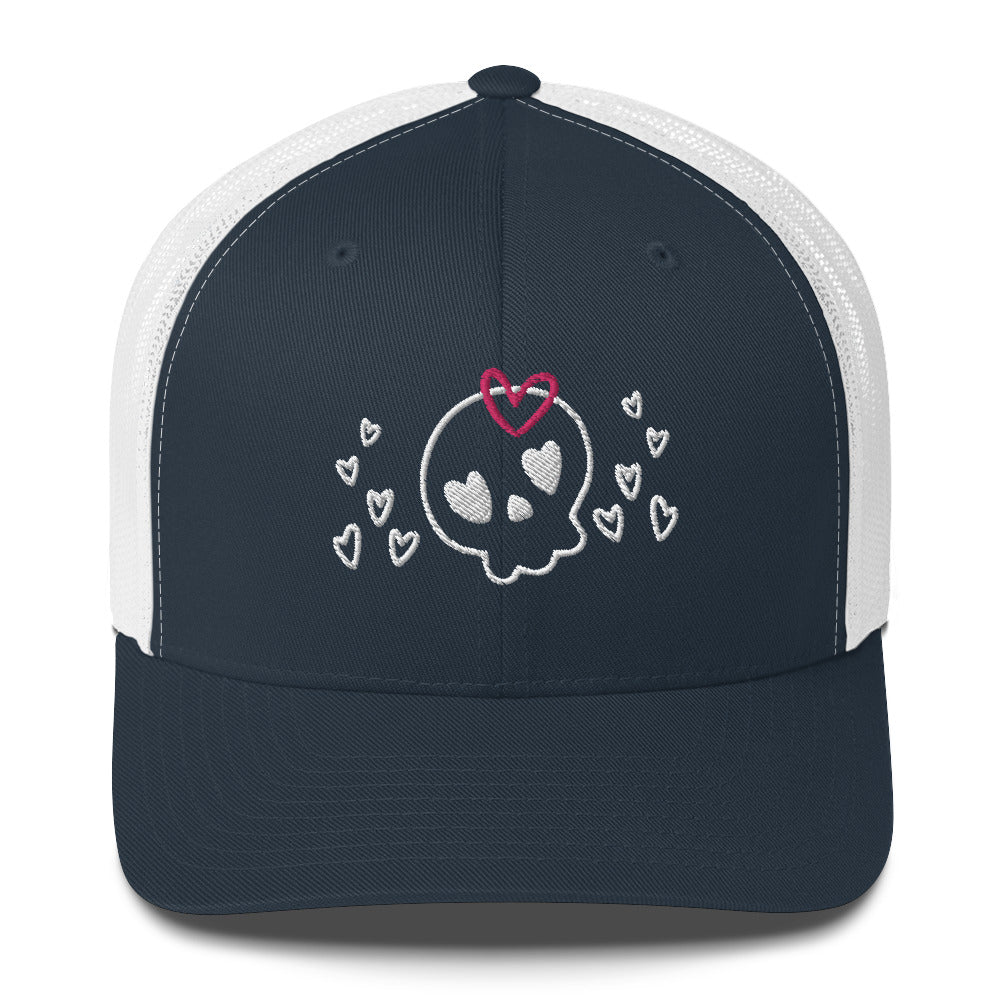 retro trucker hat/cap navy blue white, with image design of a cartoonish cute skull with heart eyes, a heart bow, and stars. Front view.