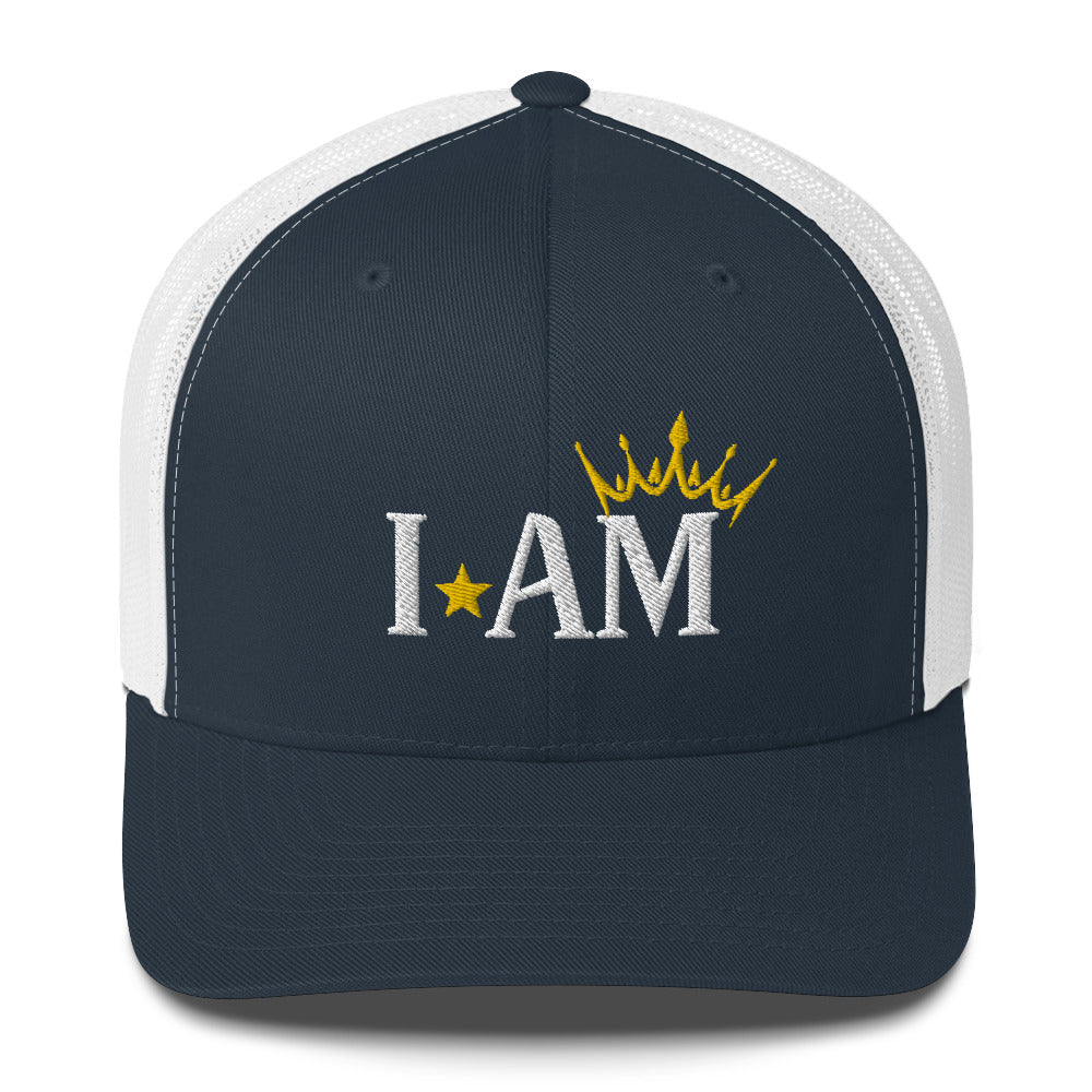 retro trucker hat navy blue white, with image phrase: "I AM," with image graphic of a gold crown over the letter M. Front view.