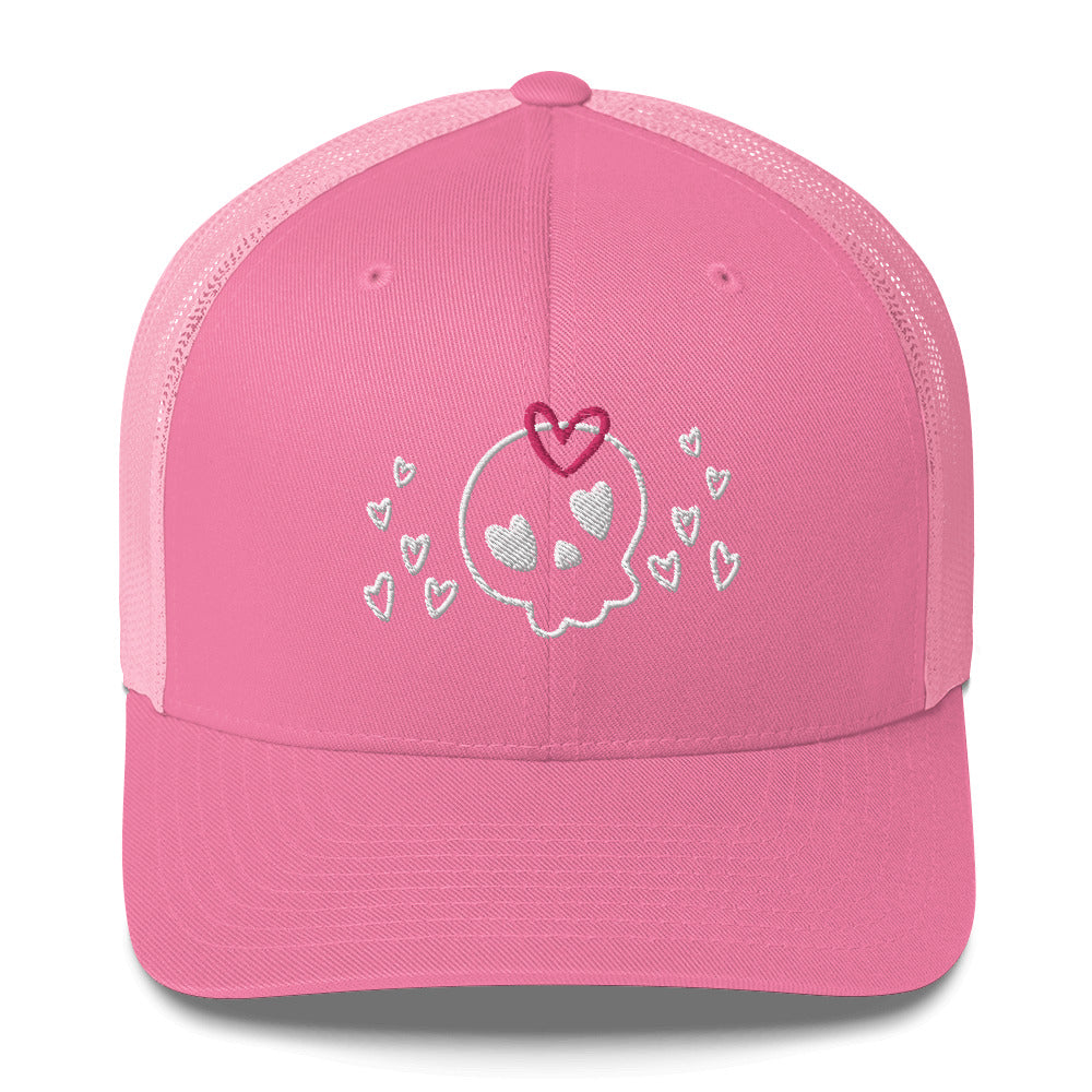 retro trucker hat/cap pink , with image design of a cartoonish cute skull with heart eyes, a heart bow, and stars. Front view.