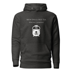 Unisex charcoal grey heather hoodie with image phrase: "Brew spells, not tea (pinche chismosa)." Underneath words is an image of a cauldron decorated with stars and skull with crossbones. Front view. Halloween, spooky season.