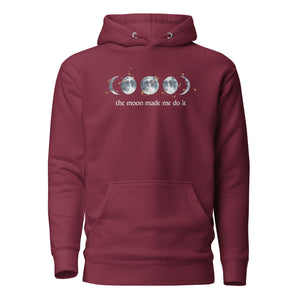 unisex maroon hoodie with image phrase "The moon made me do it." With image graphic of watercolor moon phases, decorated with random gold star constellations. Front view.