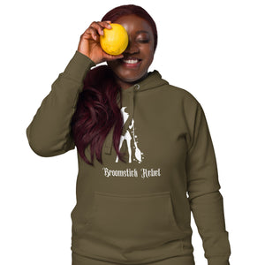 Woman modeling/wearing military army green unisex hoodie, with pockets. Image design: silhouette of a pretty witch holding a magical broom, stars. Image phrase: Broomstick rebel. Front view.