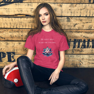 woman modeling/wearing unisex heather raspberry pink t-shirt, with image phrase: "The quiet mind hears the Universe." Image of watercolor pink and blue lotus flower floating on water.