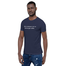 Load image into Gallery viewer, man modeling/wearing unisex navy blue t-shirt, with image phrase: &quot;only in darkness can we find the light within.&quot; Front view.
