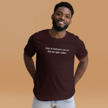 Load image into Gallery viewer, man modeling/wearing unisex oxblood black t-shirt, with image phrase: &quot;only in darkness can we find the light within.&quot; Front view.
