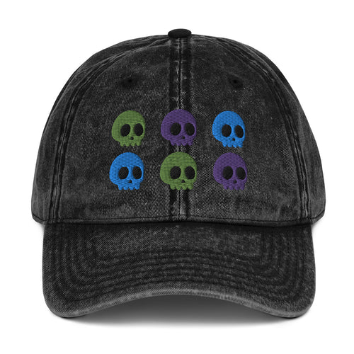 vintage denim cap black , with image design of 6 purple, green, and blue skulls, 2 of each color, in two rows.  Front view.